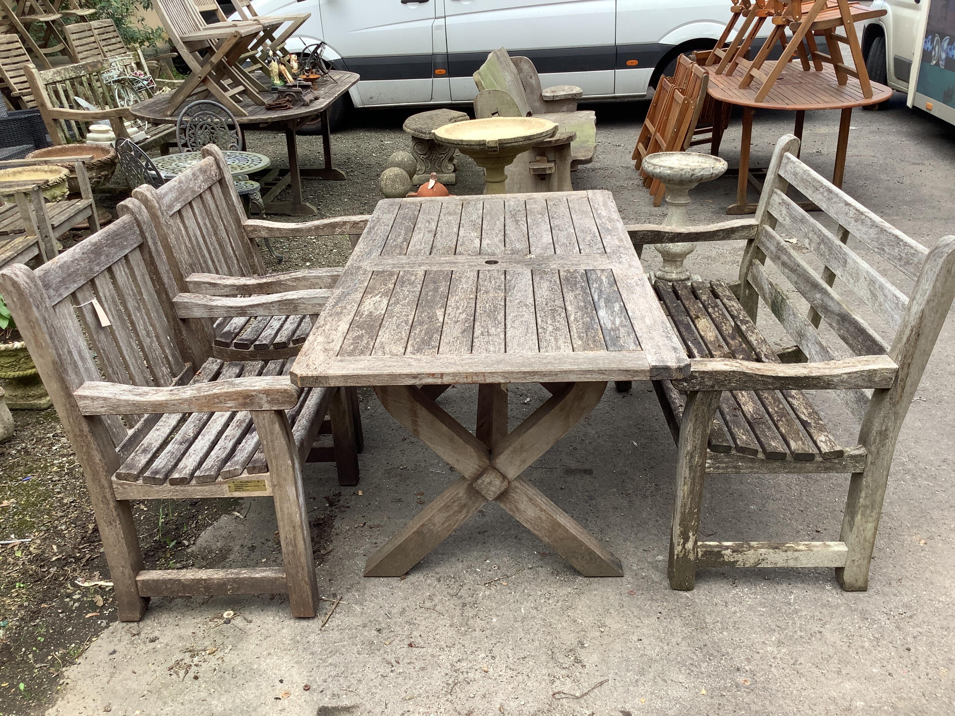 A rectangular weathered teak garden table, width 152cm, depth 86cm, height 74cm, together with a teak garden bench and two armchairs